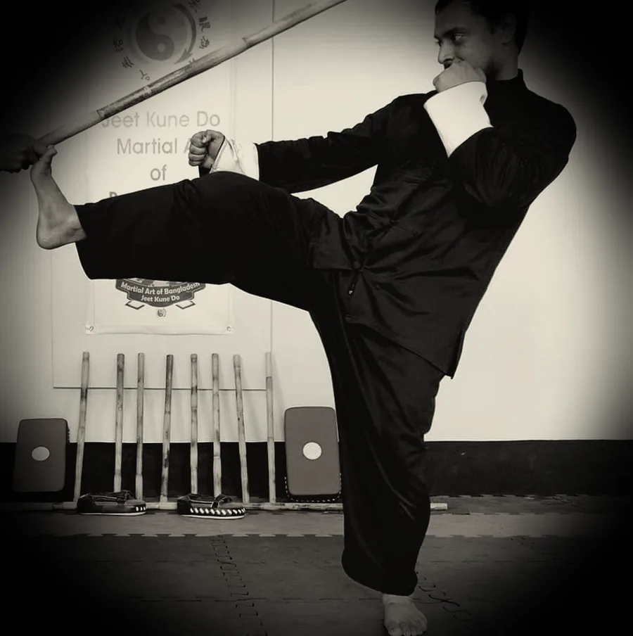 JKDBD student holding a long stick in a balanced stance, demonstrating footwork and timing